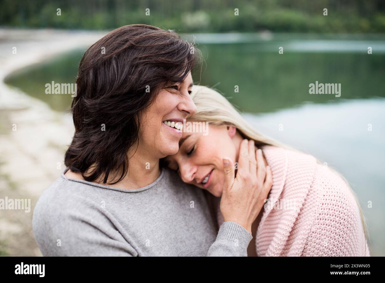 Fille adulte passant du temps avec sa mère. Maman et fille embrassant à l'extérieur, debout près du réservoir, le remblai du lac. Inconditionnel, profond Banque D'Images