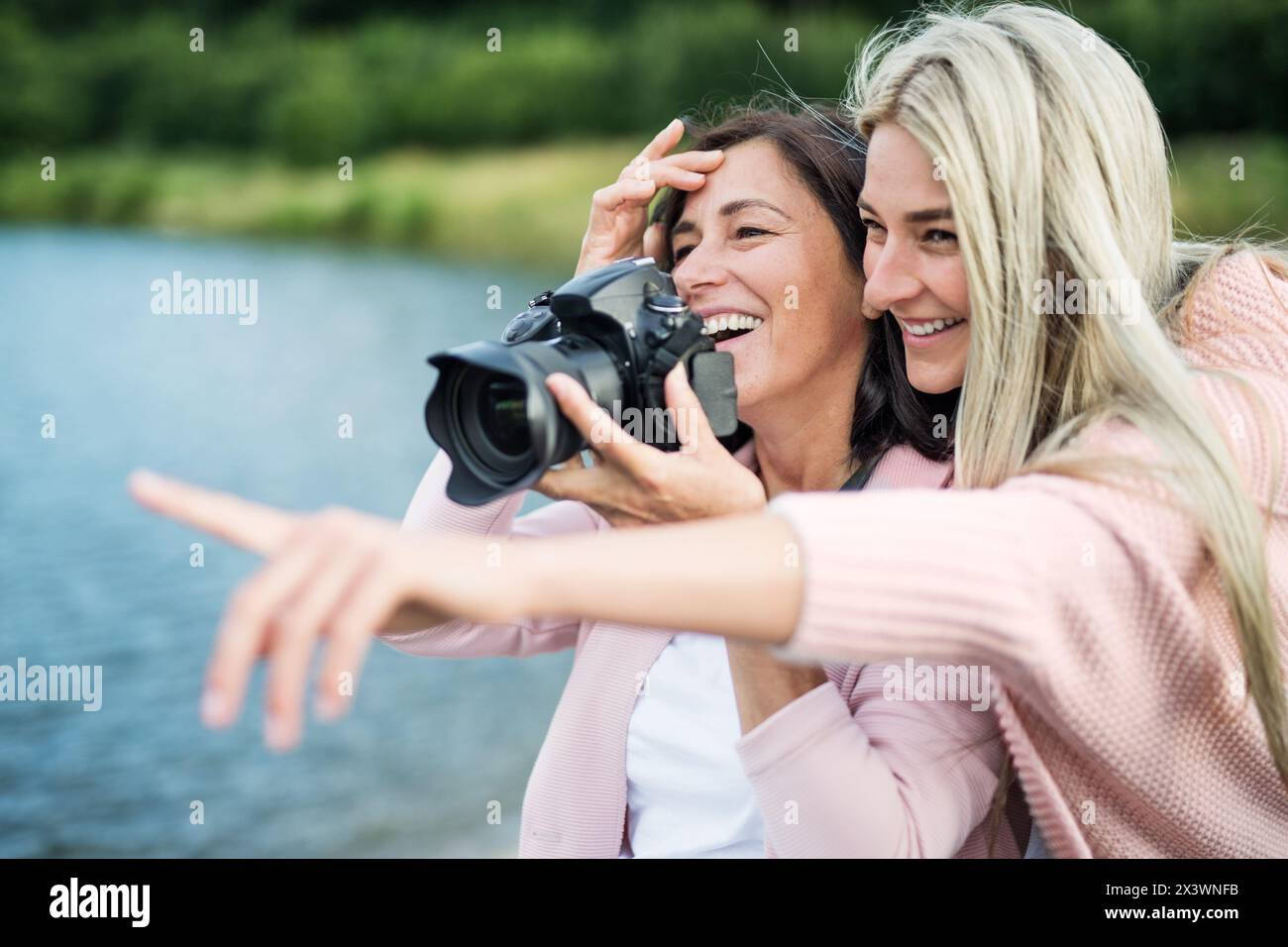 Fille adulte enseignant à la mère comment prendre des photos avec un appareil photo professionnel, expliquant la technologie, riant. Concept de fête des mères. Banque D'Images