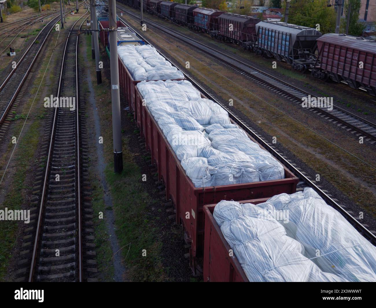 Un long train de marchandises avec des wagons sans toit chargé d'énormes sacs blancs et attendant à la gare de Kiev, Ukraine. Banque D'Images
