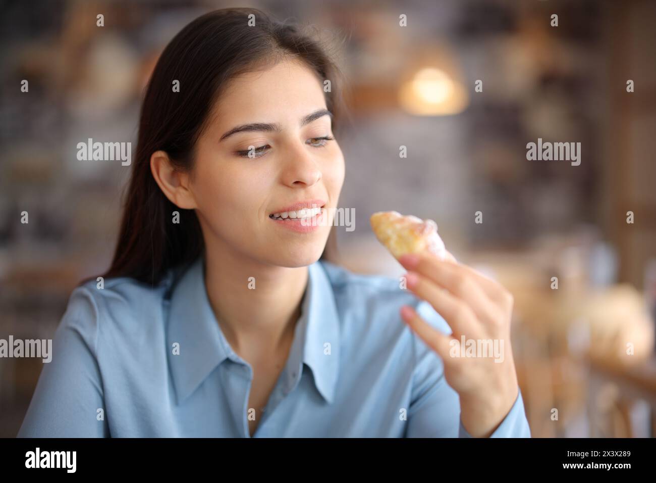 Femme dans un intérieur de restaurant mangeant boulangerie Banque D'Images