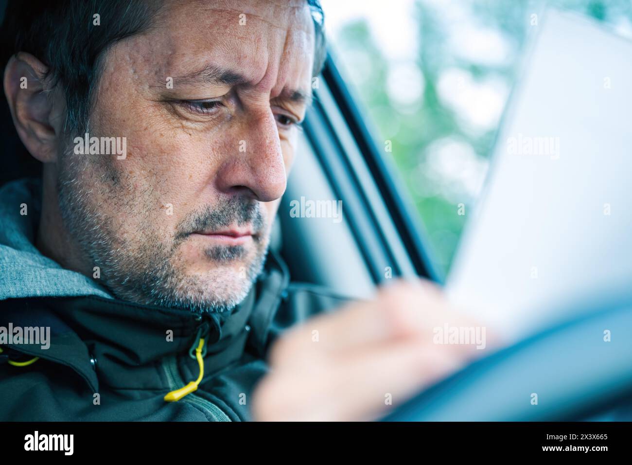 Conducteur masculin lisant un document papier dans la voiture, focus sélectif Banque D'Images