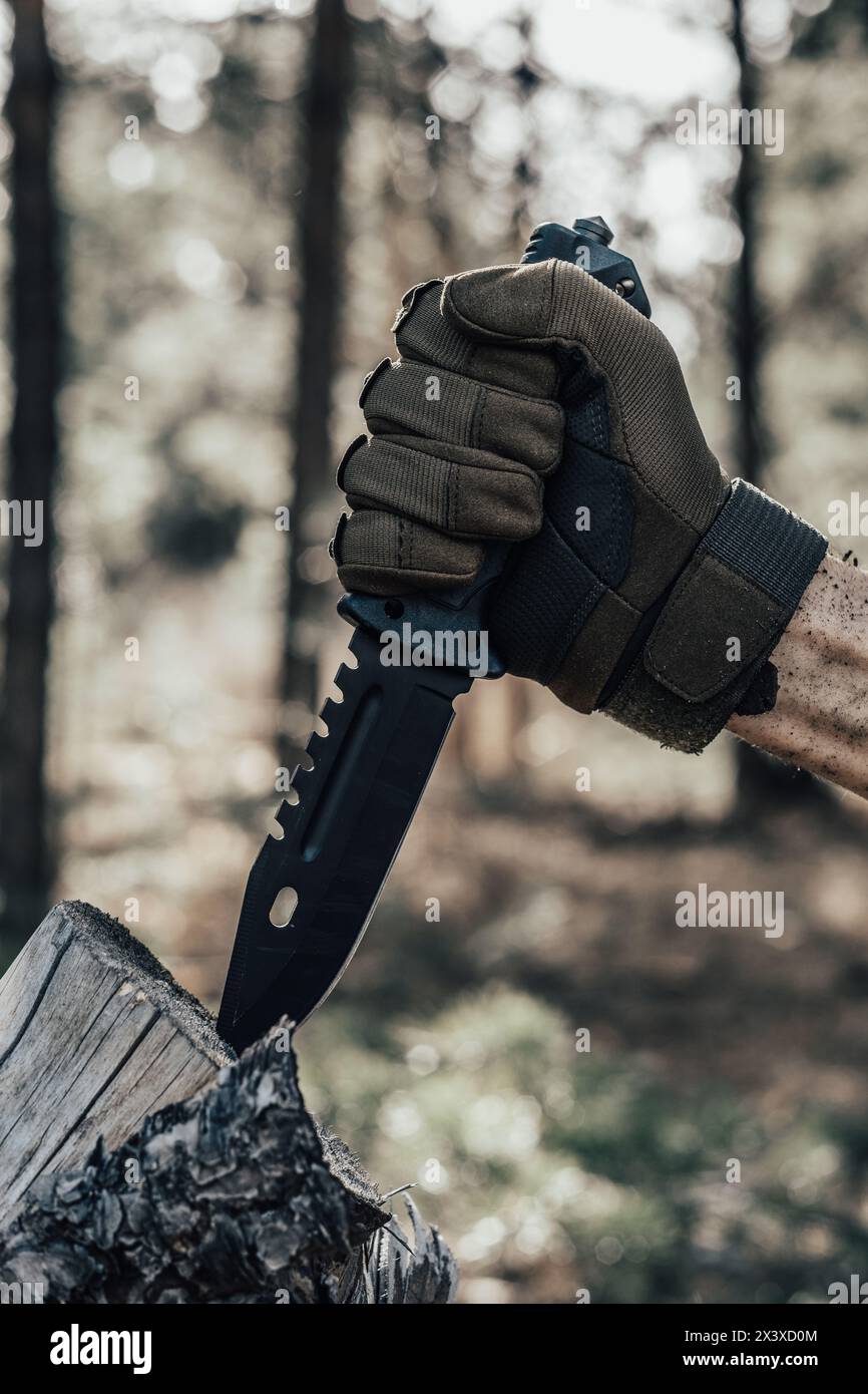 La main de l'homme tient un couteau dans la forêt. Concept de survie et de survie Banque D'Images