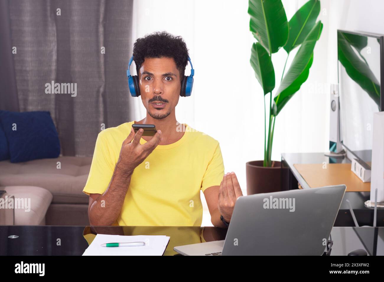 Homme noir portant un T-shirt jaune à Remote Job. Jeune nomade numérique sur une réunion de télétravail à Desk avec ordinateur portable Banque D'Images