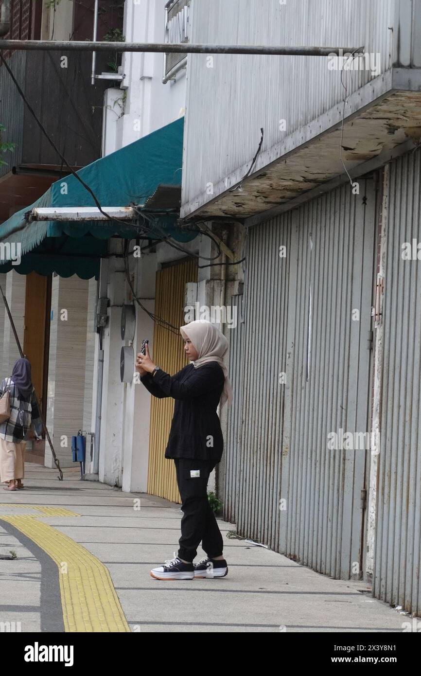 Une femme se tenait debout pour prendre une photo de son amie sur le trottoir près d'un magasin fermé Banque D'Images