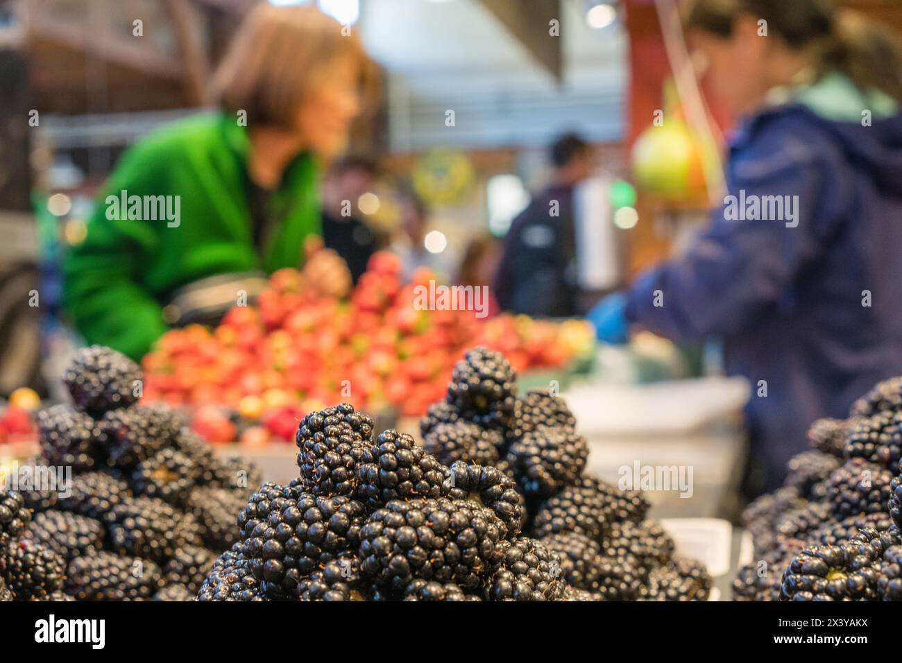 Le 10 août 2023-Vancouver, C.-B., Canada-gros plan sur des boîtes de baies biologiques fraîches colorées exposées dans un marché agricole avec des gens qui magasinent à l'arrière-plan. Banque D'Images