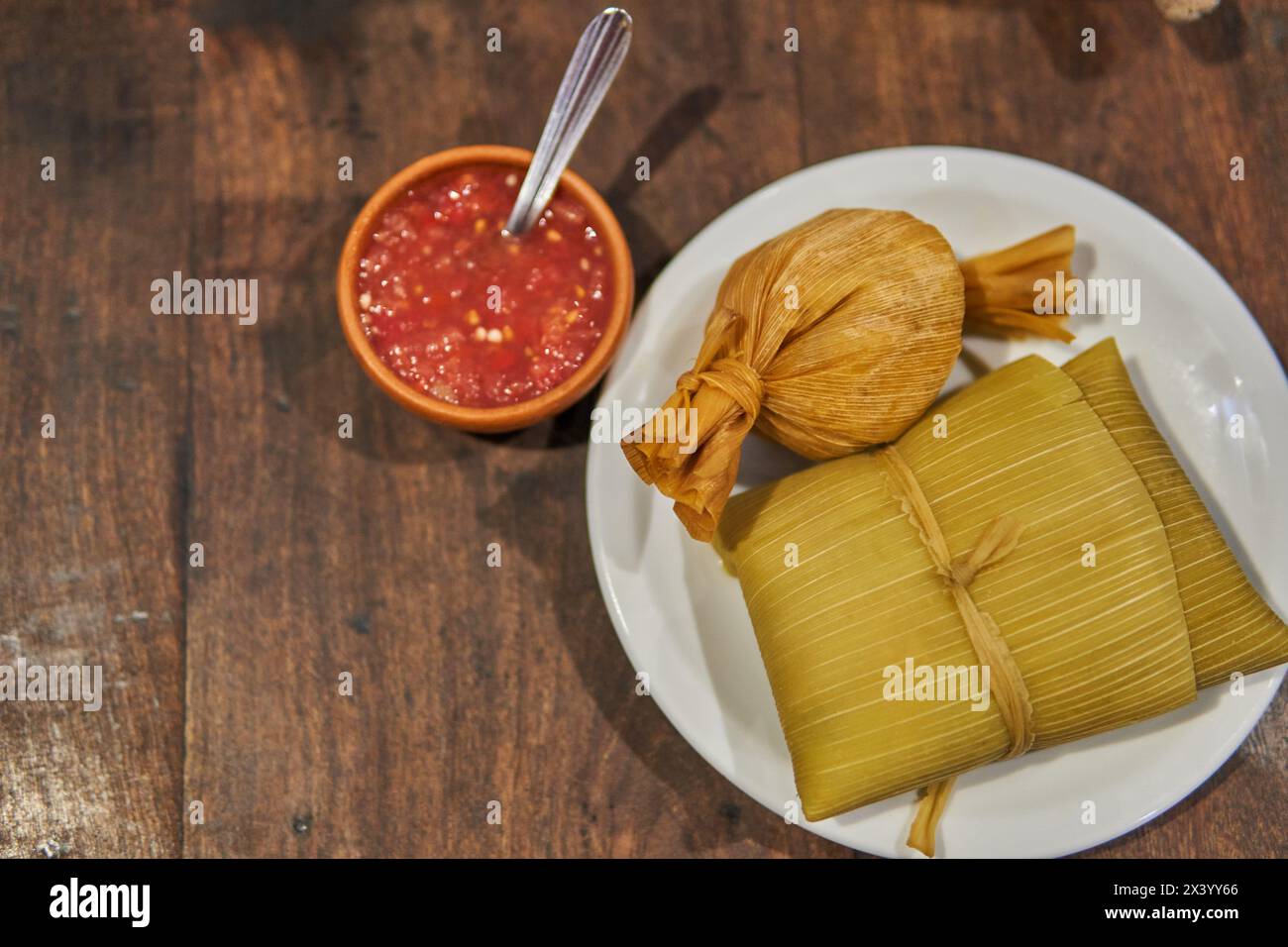 Tamale et humita maison sur une assiette blanche avec une sauce rouge sur le côté, nourriture typique du nord de l'Argentine. Feuilles de maïs farines de maïs farcies dou Banque D'Images