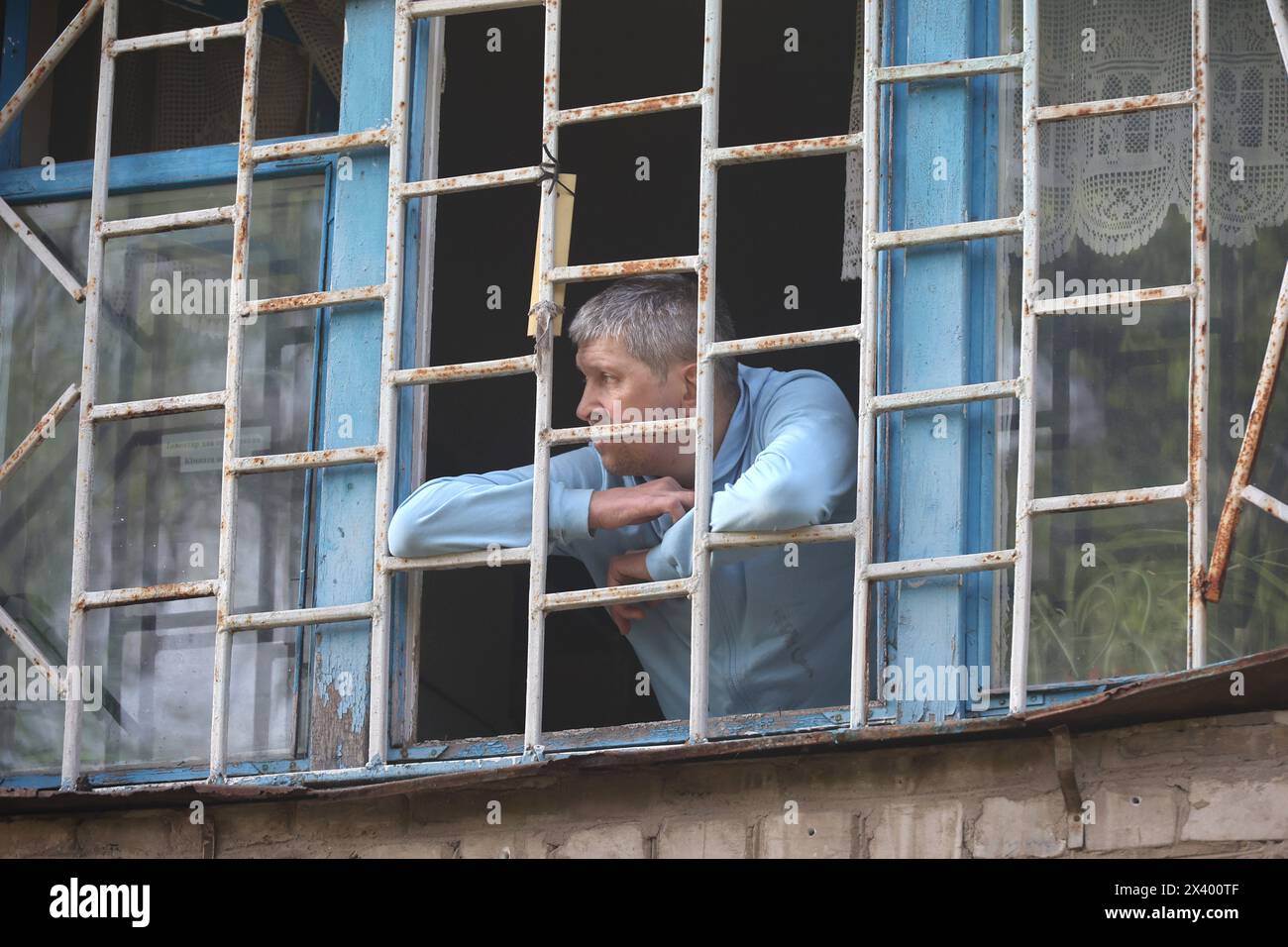 KHARKIV, UKRAINE - 27 AVRIL 2024 - Un homme regarde par une fenêtre grillagée à l'hôpital psychiatrique N3 dans le district de Saltivskyi après une frappe nocturne de missiles russes S-300, à Kharkiv, dans le nord-est de l'Ukraine. Le 27 avril à 00h30 heure locale, les troupes russes ont attaqué l'hôpital psychiatrique N3 à Kharkiv avec des missiles de défense aérienne S-300. Les fenêtres, le toit, le bâtiment hors service, le bloc alimentaire, la chaufferie et d'autres bâtiments ont été endommagés. Une femme de 53 ans a été blessée. Il y avait 60 patients et 5 membres du personnel hospitalier pendant la grève. Banque D'Images