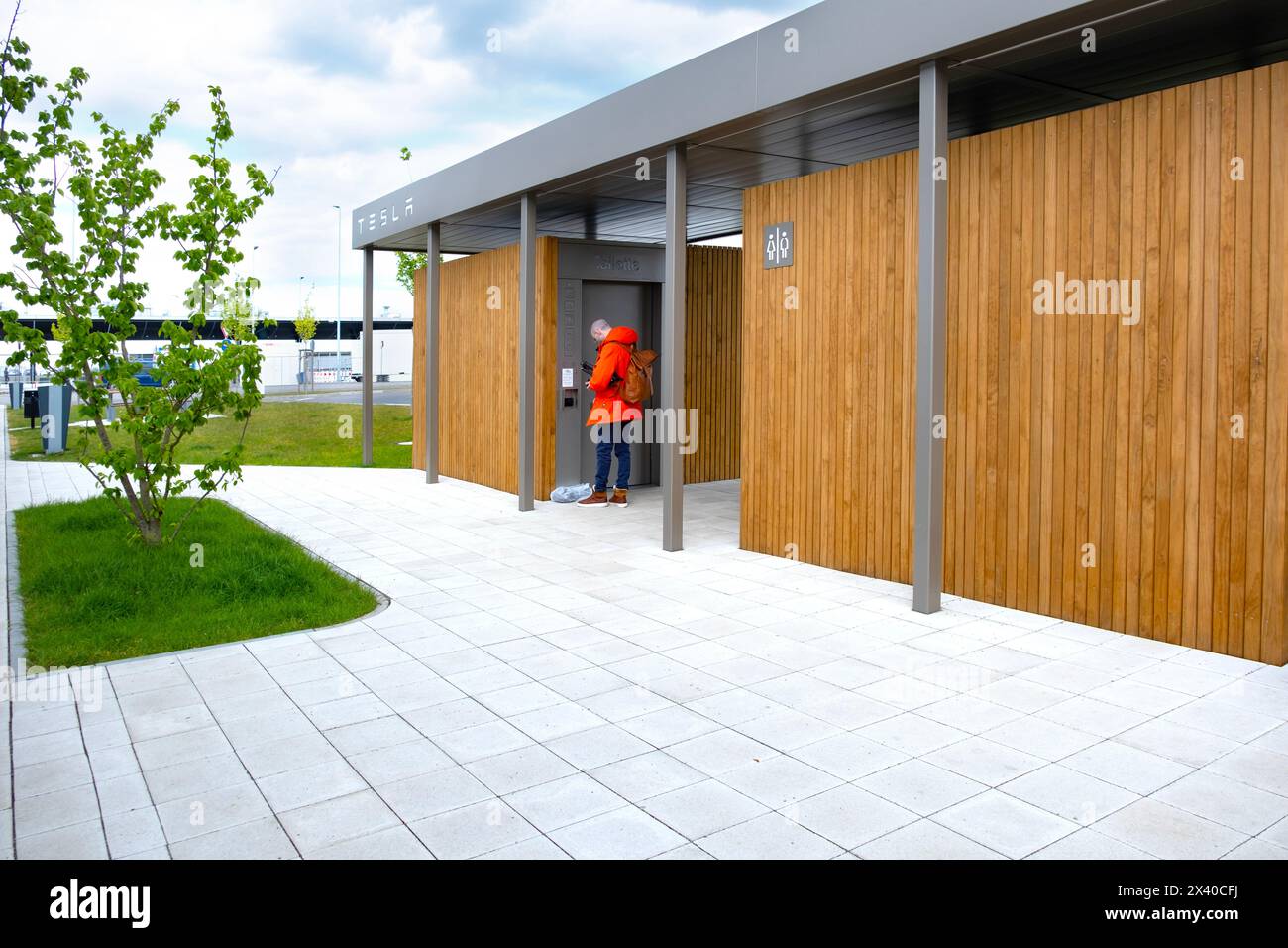 Homme visitant les toilettes publiques dans Tesla-Supercharger Lounge, chargeur de puissance ev en Europe, routine quotidienne d'assainissement, vie moderne, Berlin, Allemagne - avril 26 Banque D'Images