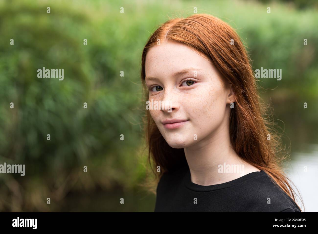 Fille de 12 ans aux cheveux rouges avec des roussettes posant avec un fond de bokeh nature, Bruxelles, Belgique Banque D'Images