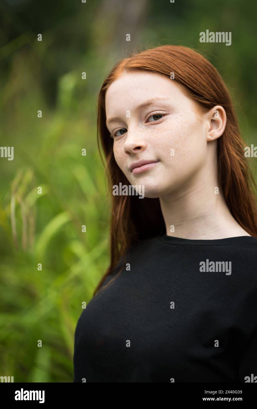 Fille de douze ans aux cheveux rouges avec des taches de rousseur posant avec un fond de bokeh nature. Autorisation du modèle. Banque D'Images