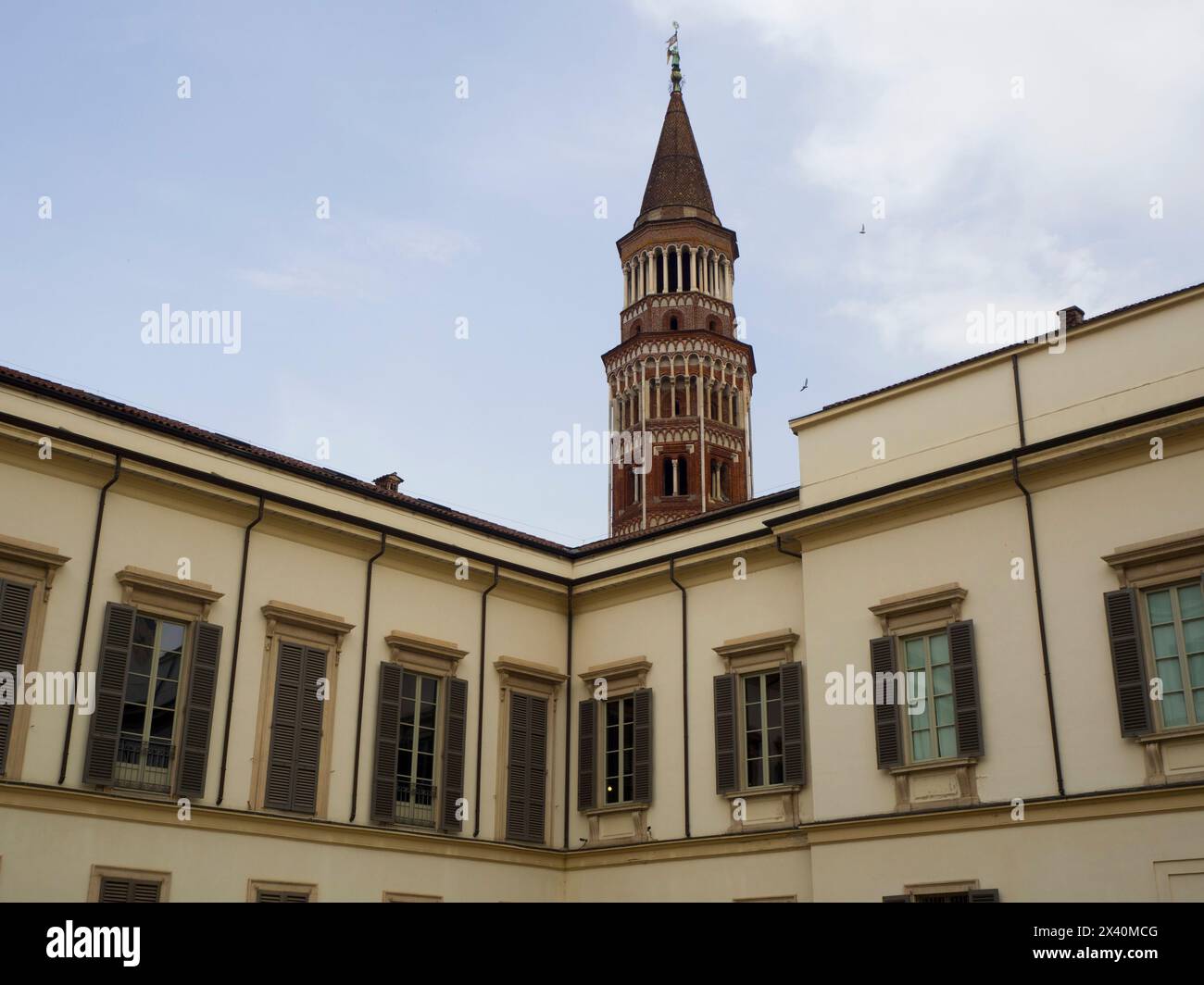Section supérieure avec fenêtres et volets en bois de l'extérieur du Palais Royal et clocher de San Gottardo in Corte église à Milan ; Milan, Italie Banque D'Images