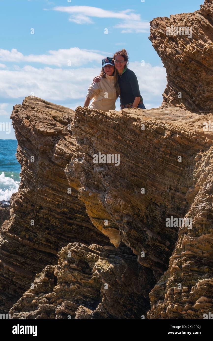 Deux femmes s'embrassent au sommet d'un rocher stratifié au Crystal Cove State Park près d'Irvine, Californie, États-Unis ; Californie, États-Unis d'Amérique Banque D'Images
