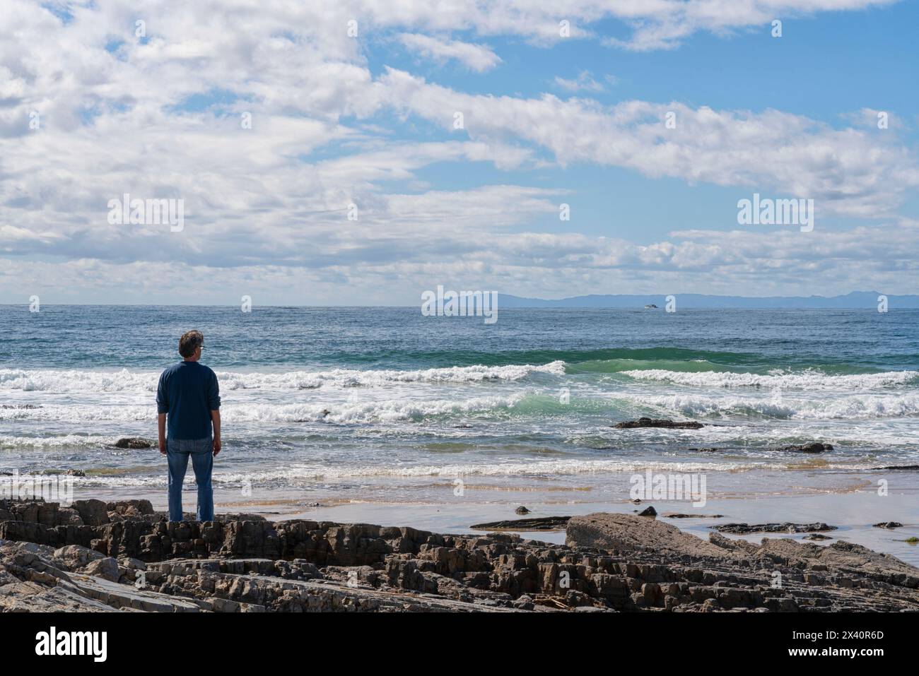 Homme debout sur les rives de l'océan Pacifique regardant les vagues entrer ; Irvine, Californie, États-Unis d'Amérique Banque D'Images