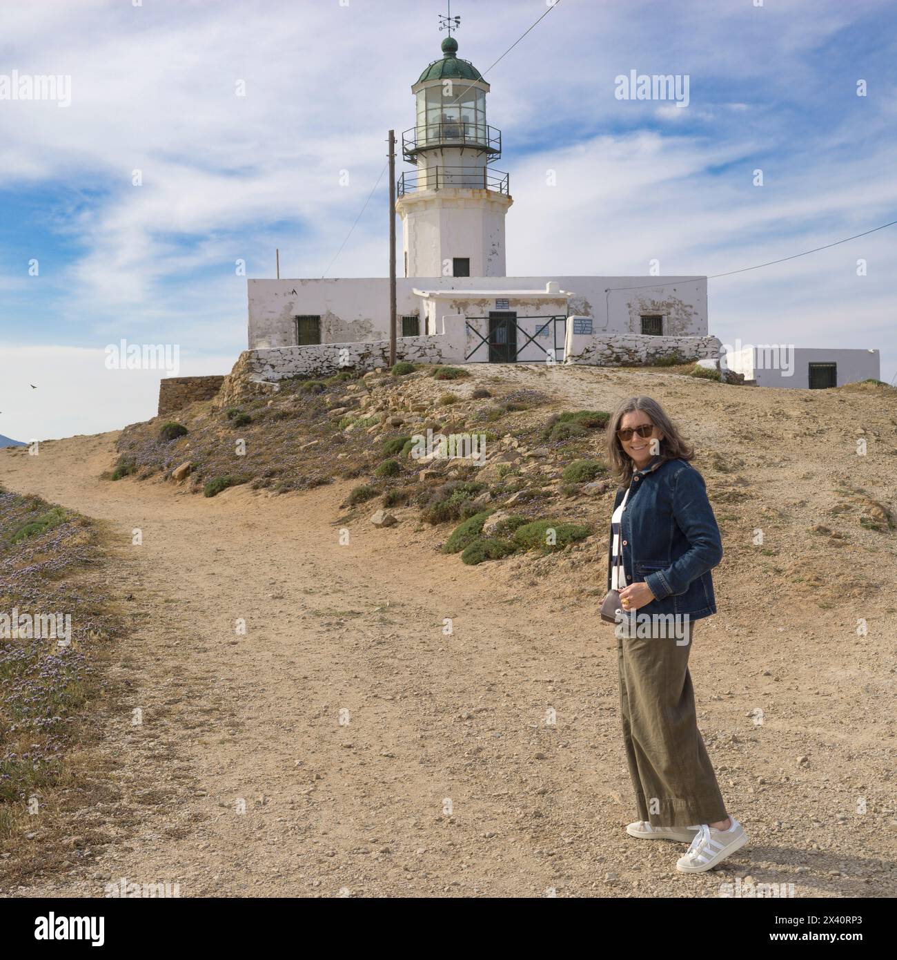 Touriste senior visite le phare d'Armenistis, un phare emblématique abandonné sur la côte de Mykonos ; Mykonos, Grèce Banque D'Images