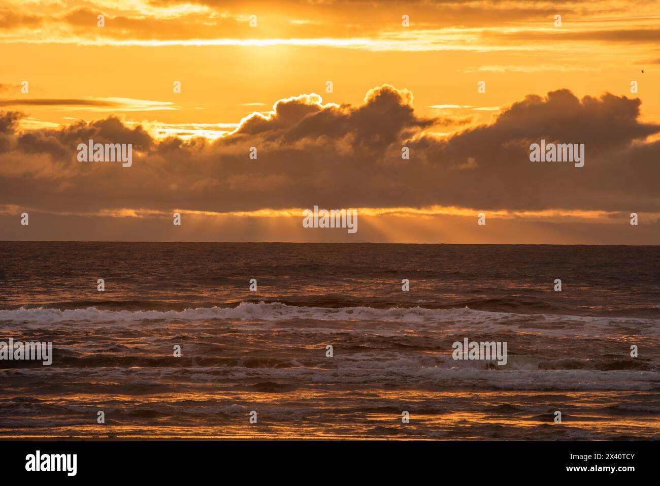 Beau coucher de soleil avec les doigts de Dieu s'étendant vers le bas de derrière les nuages au-dessus de l'océan Pacifique de la plage à Cape Disception State Park ... Banque D'Images