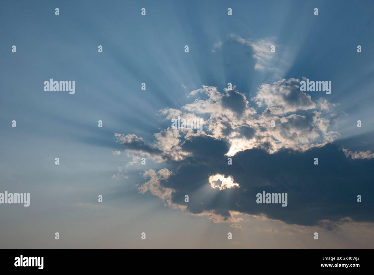 La lumière du soleil coule d'une formation de nuages sombres et illumine un ciel bleu ; Lac des bois, Ontario, Canada Banque D'Images