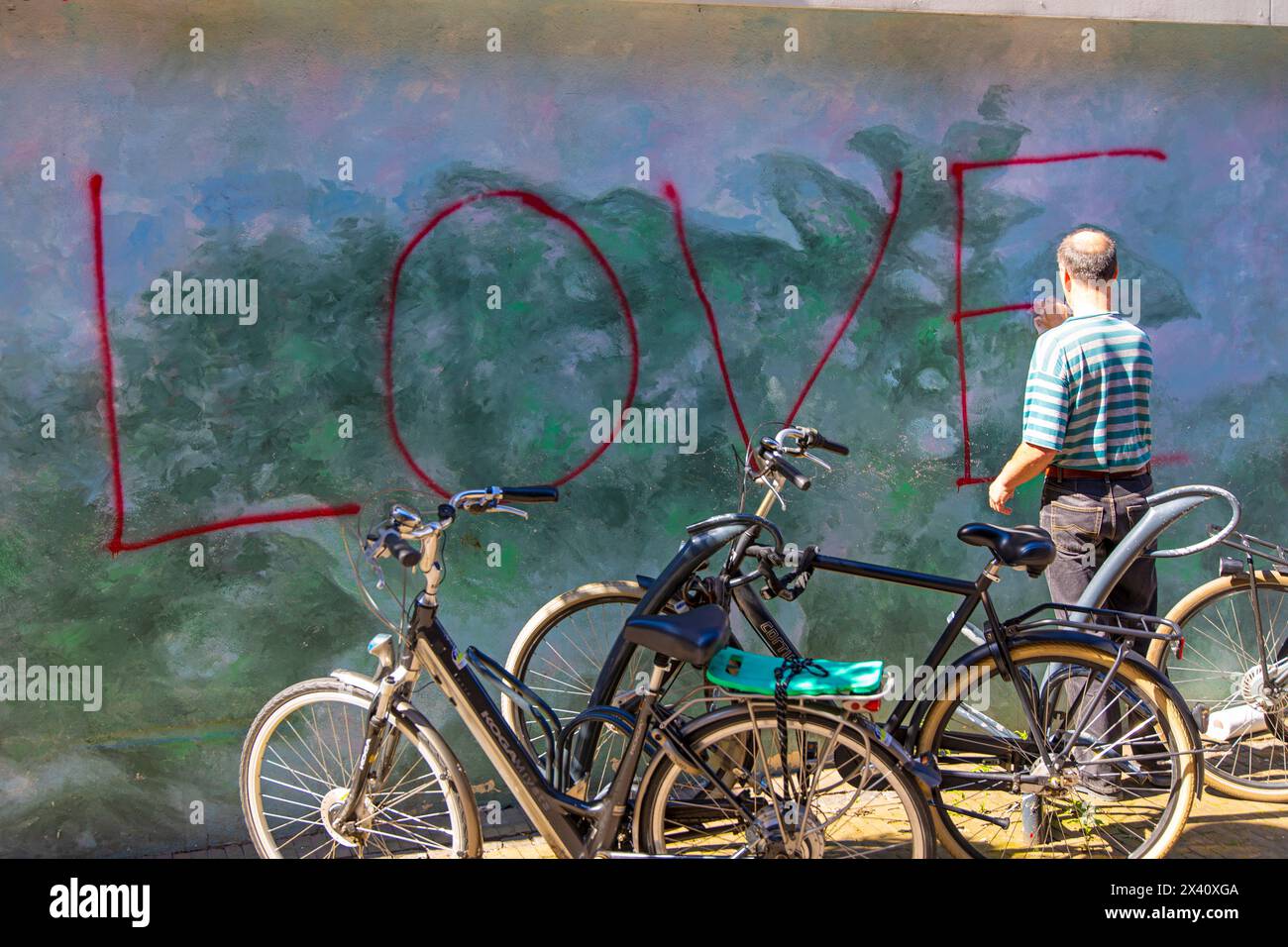 Mur avec graffiti. Un homme efface la peinture Banque D'Images