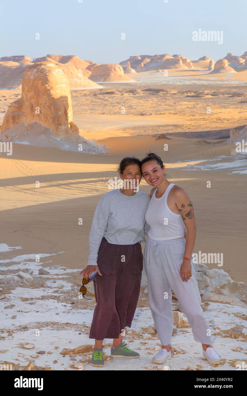Mère et fille touristes debout dans le désert blanc égyptien avec des formations calcaires au coucher du soleil ; Egypte Banque D'Images