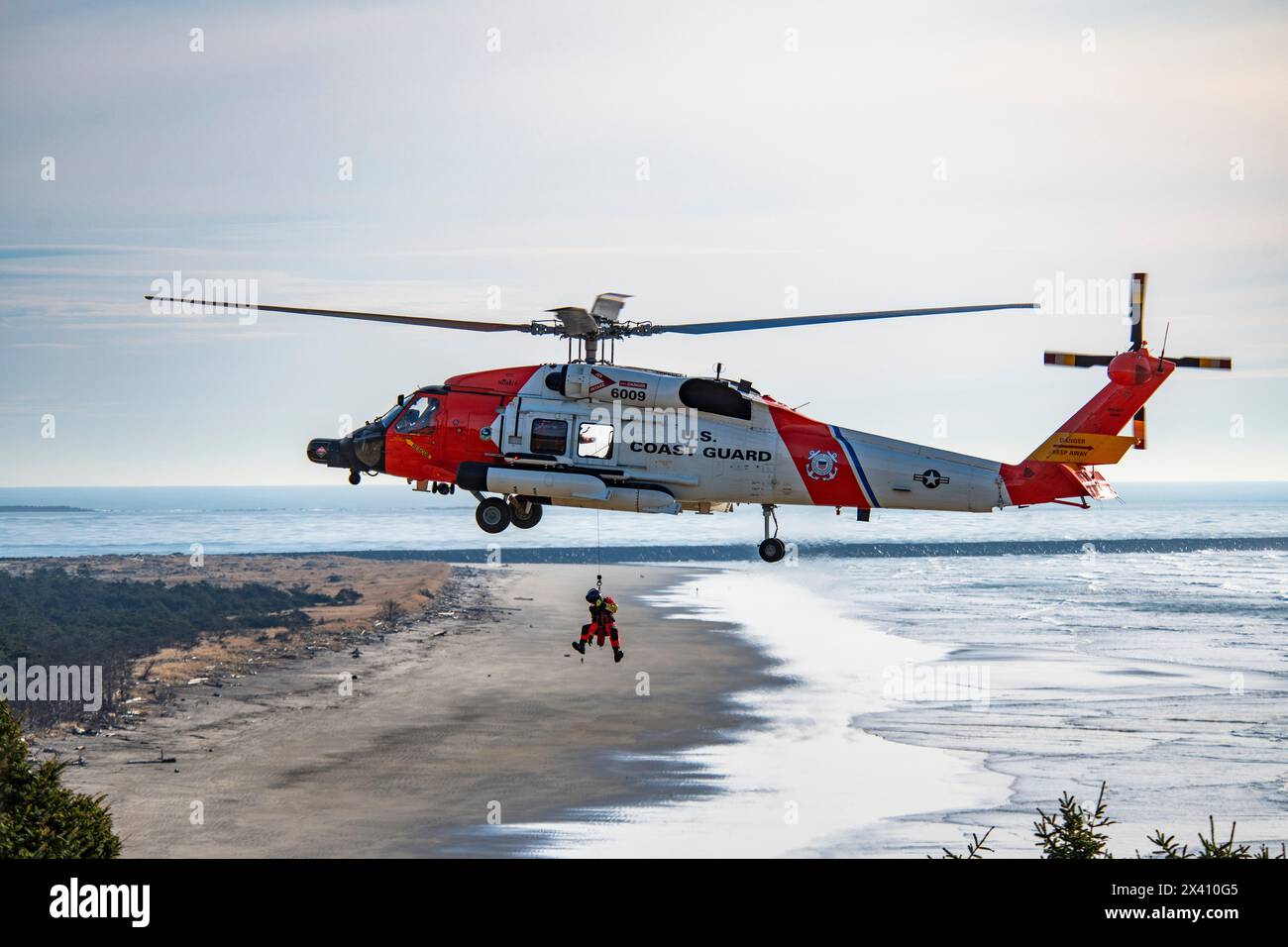 L'équipage de la Garde côtière américaine suspendu en dessous d'un Sikorsky MH-60J Jayhawk effectuant des exercices de sauvetage au parc d'État Cape Disception près du Mo... Banque D'Images