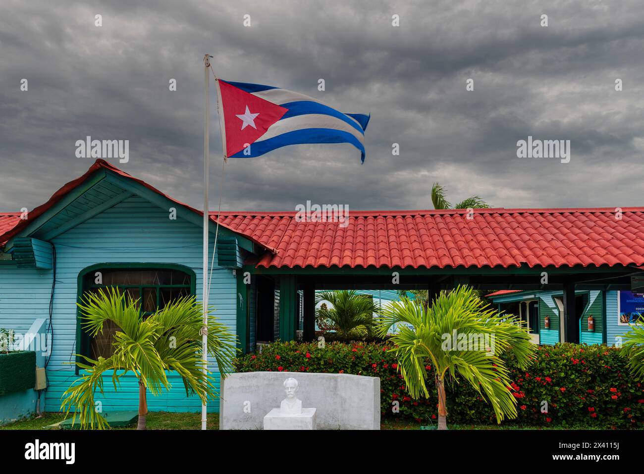 Drapeau national de Cuba flottant à l'extérieur d'un bâtiment turquoise ; Cayo Guillermo, Cuba Banque D'Images