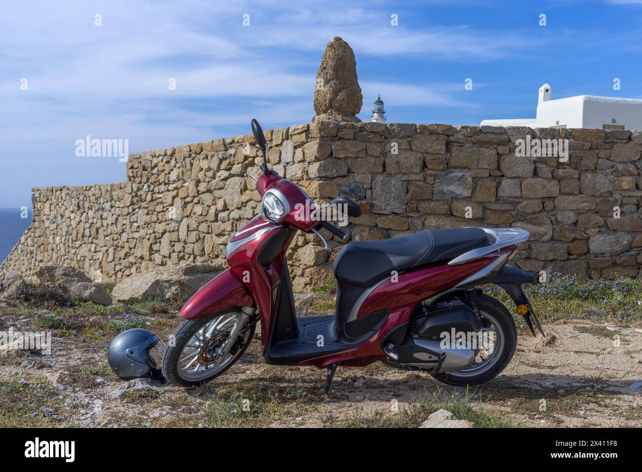 Moto garée le long d'un mur de pierre sur une île grecque ; Mykonos, Grèce Banque D'Images