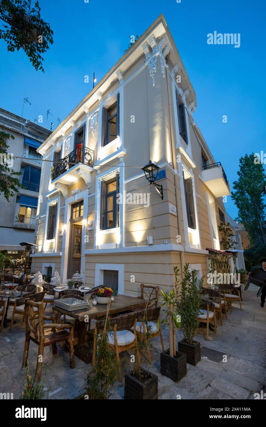 Patio extérieur à manger à l'extérieur d'un bâtiment jaune éclairé au crépuscule ; Athènes, Grèce Banque D'Images