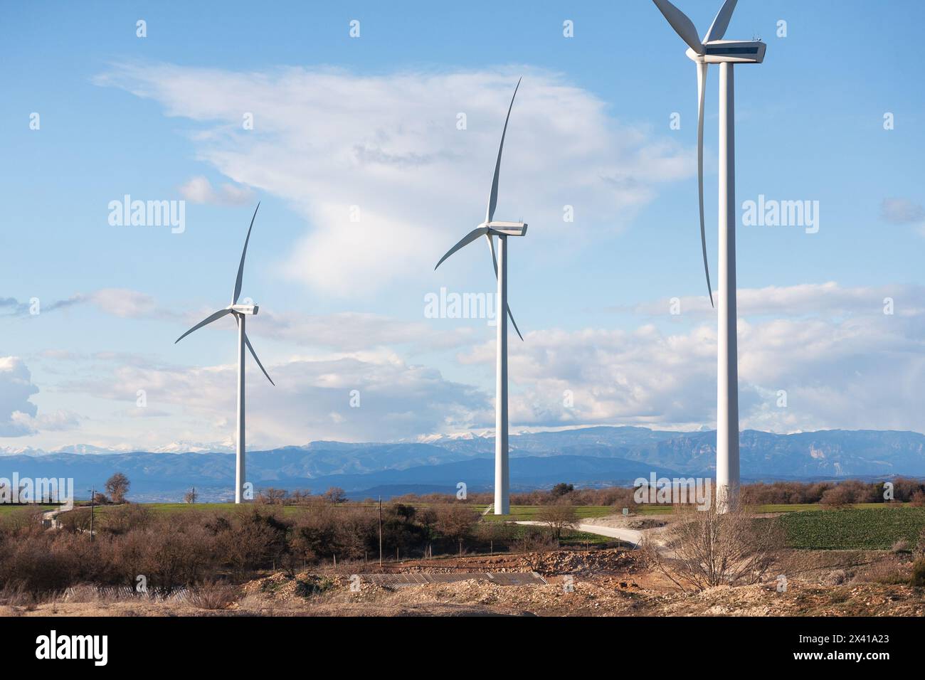 Trois éoliennes sont debout dans un champ avec un ciel nuageux en arrière-plan. La scène est calme et paisible, car les turbines ne sont pas en mouvement et le Banque D'Images