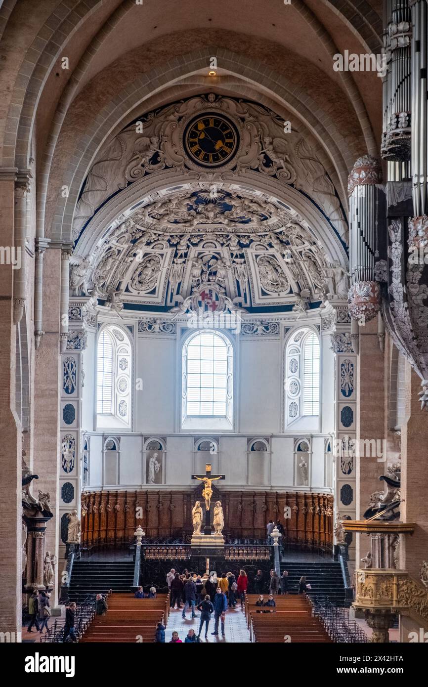Trèves, Rijnland-Palts, Allemagne, 23 mars 2024, L'abside de la cathédrale de Trèves est magnifiquement capturée, avec un autel orné où les fidèles se rassemblent. Au-dessus, une horloge baroque se dresse comme une sentinelle intemporelle au milieu d'un éventail étonnant de reliefs sculpturaux. Le crucifix est central, une incarnation du noyau spirituel de la cathédrale, tandis que les éléments architecturaux environnants parlent de siècles d'art religieux et de tradition. Autel orné et horloge baroque de l'abside de la cathédrale de Trèves. Photo de haute qualité Banque D'Images