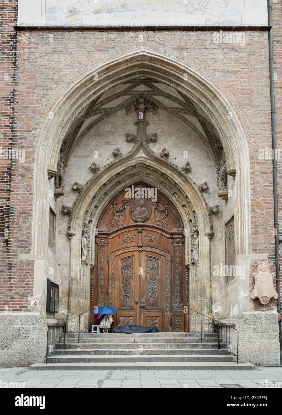 Munich, Allemagne - 21 déc. 2023 - Un sans-abri couchant dur ou pauvre mendiant sans-abri couché sur le sol dans un sac de couchage noir sur le trottoir des marches fr Banque D'Images