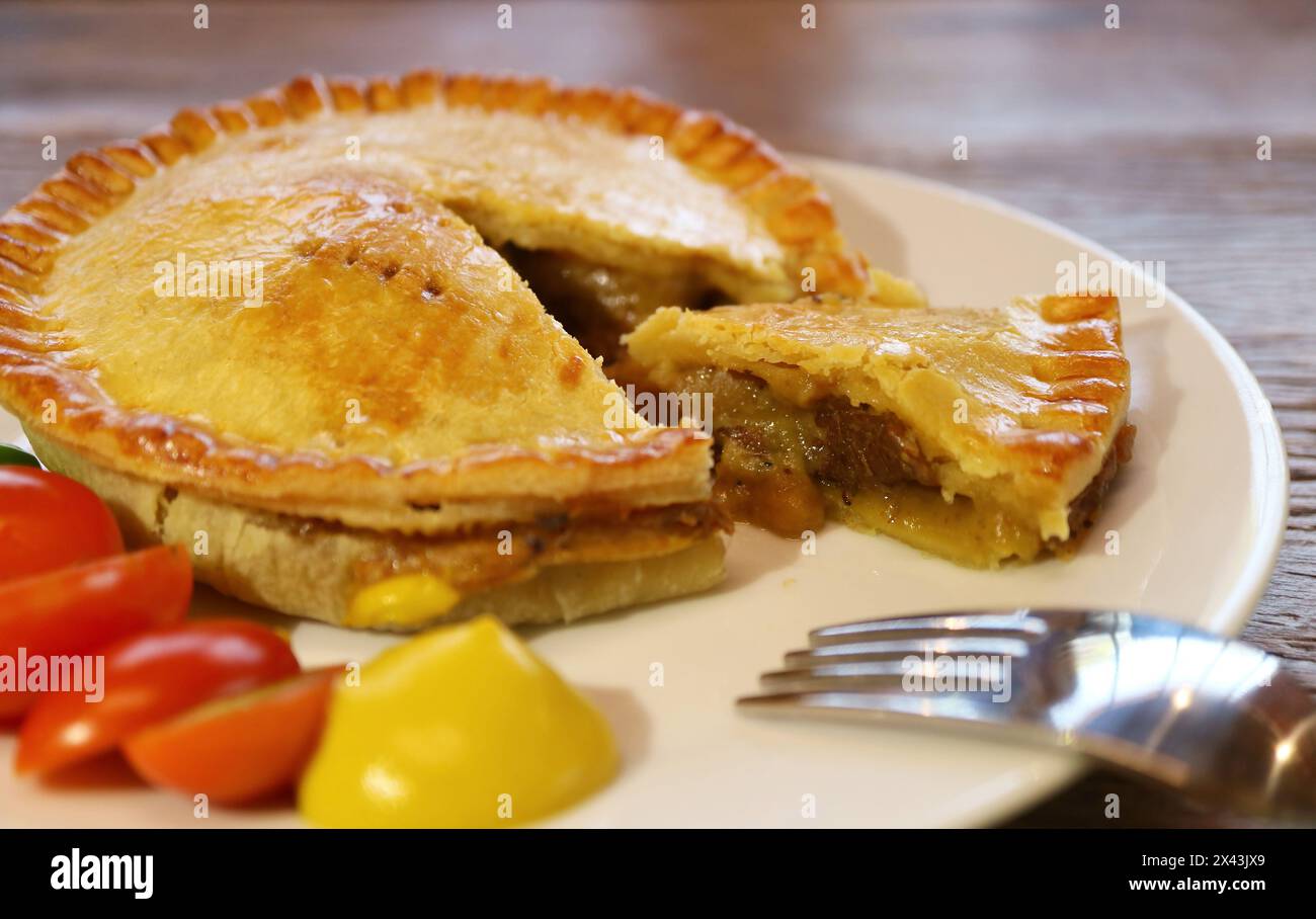Une assiette de délicieux tarte au bœuf brun doré servie sur une table en bois Banque D'Images