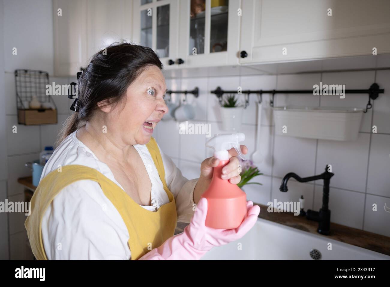 Femme folle, femme au foyer tient le détergent de nettoyage en spray, outil ménager pour diverses surfaces dans la cuisine et d'autres pièces, Spring Clean, Fresh Start, Mainta Banque D'Images