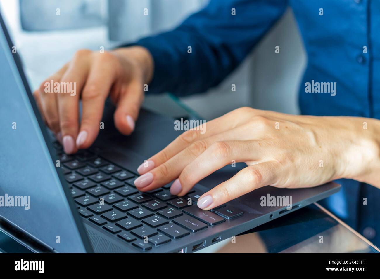 Gros plan de la femme avec de belles mains dans la tenue d'affaires, travaillant sur l'ordinateur portable dans le bureau Banque D'Images