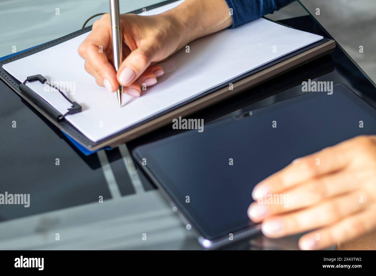 Gros plan de la femme avec de belles mains dans la tenue d'affaires, travaillant sur la tablette dans le bureau, prenant des notes Banque D'Images
