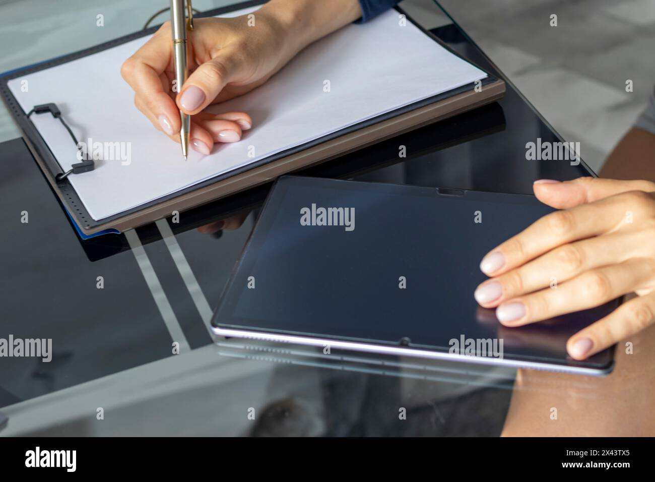 Gros plan de la femme avec de belles mains dans la tenue d'affaires, travaillant sur la tablette dans le bureau, prenant des notes Banque D'Images