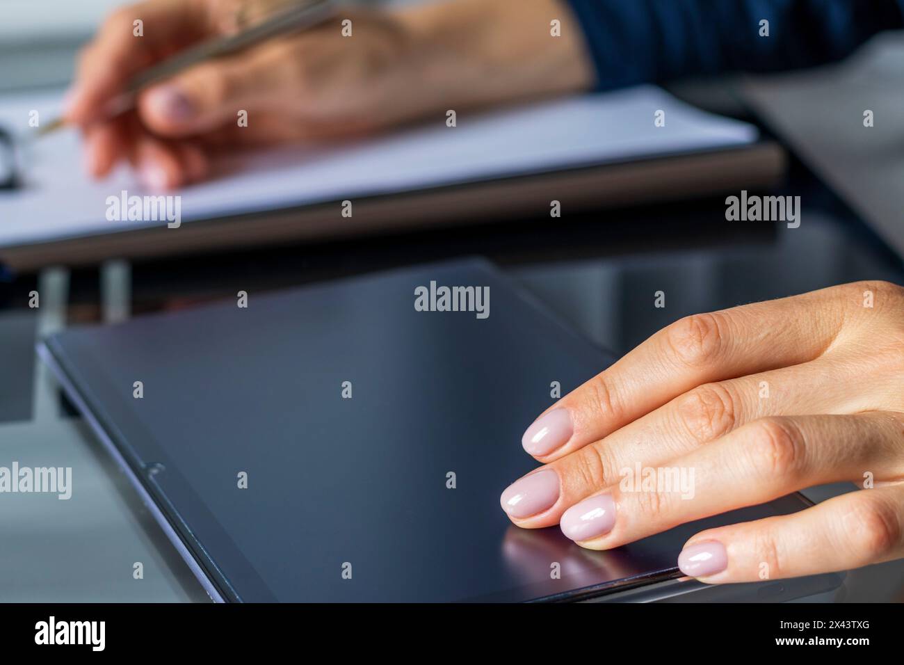 Gros plan de la femme avec de belles mains dans la tenue d'affaires, travaillant sur la tablette dans le bureau, prenant des notes Banque D'Images