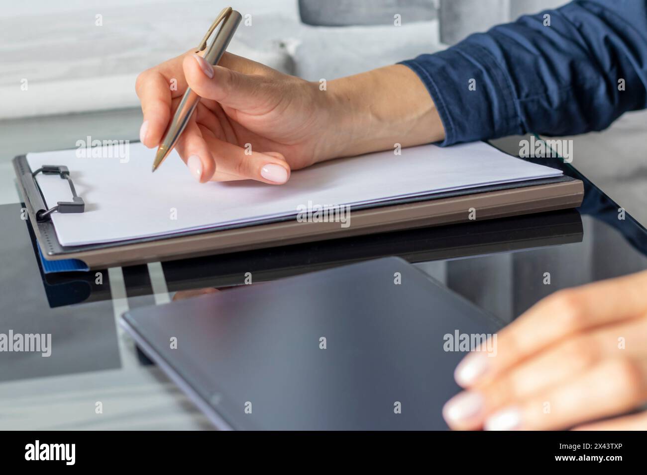 Gros plan de la femme avec de belles mains dans la tenue d'affaires, travaillant sur la tablette dans le bureau, prenant des notes Banque D'Images