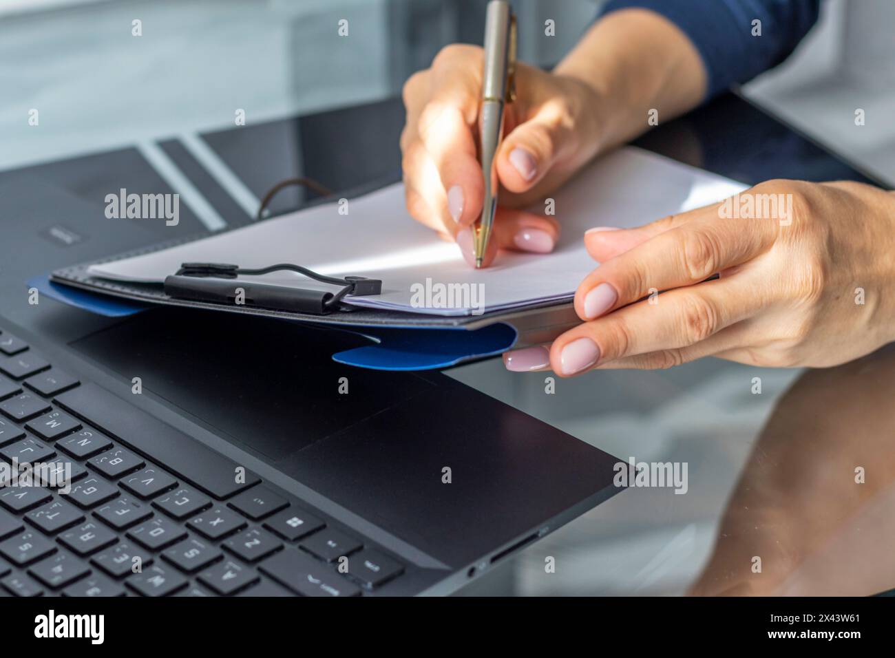 Gros plan de la femme avec de belles mains dans la tenue d'affaires, travaillant sur l'ordinateur portable dans le bureau, prenant des notes Banque D'Images