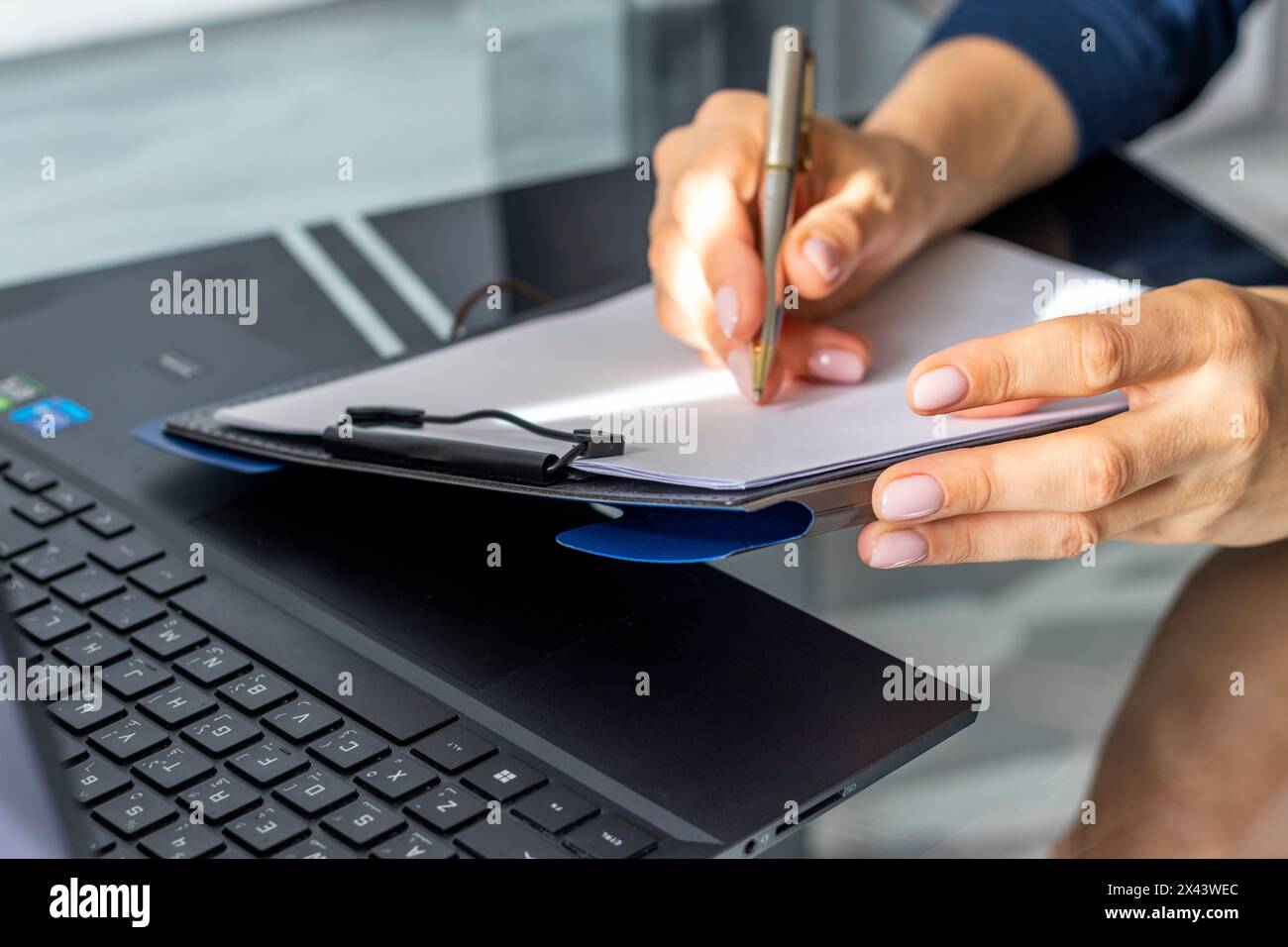Gros plan de la femme avec de belles mains dans la tenue d'affaires, travaillant sur l'ordinateur portable dans le bureau, prenant des notes Banque D'Images