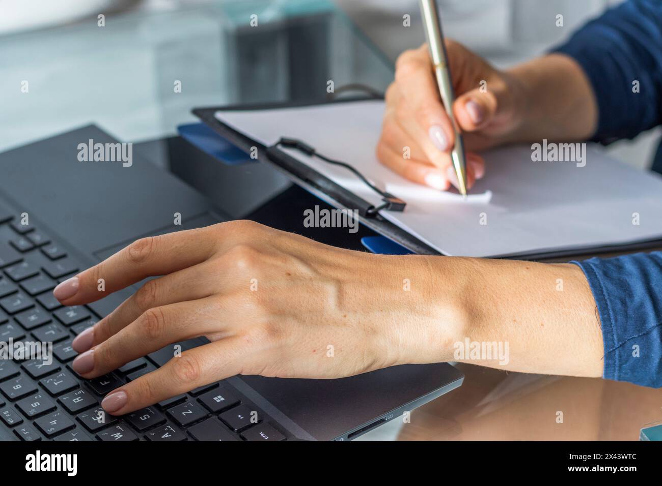 Gros plan de la femme avec de belles mains dans la tenue d'affaires, travaillant sur l'ordinateur portable dans le bureau, prenant des notes Banque D'Images