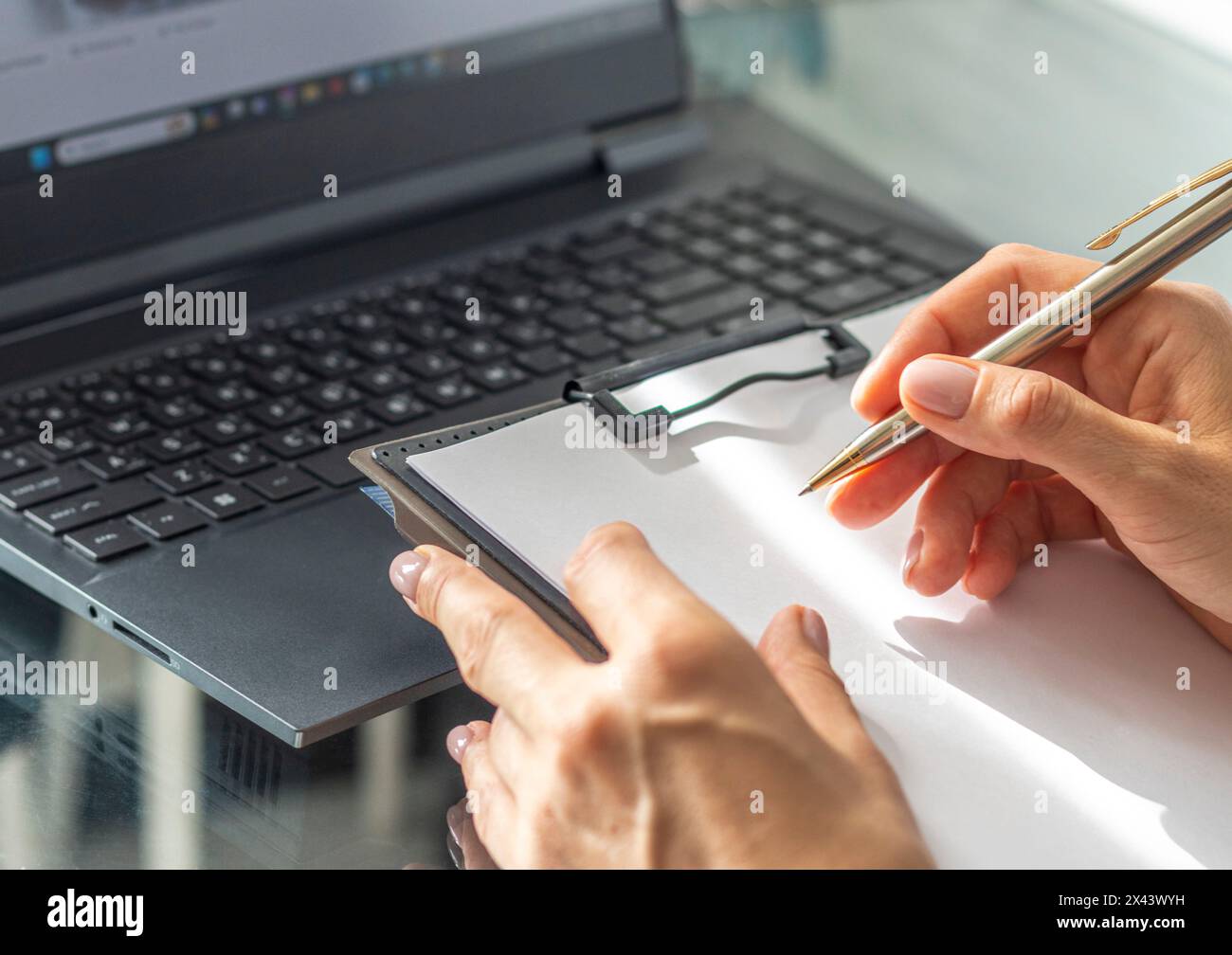 Gros plan de la femme avec de belles mains dans la tenue d'affaires, travaillant sur l'ordinateur portable dans le bureau, prenant des notes Banque D'Images
