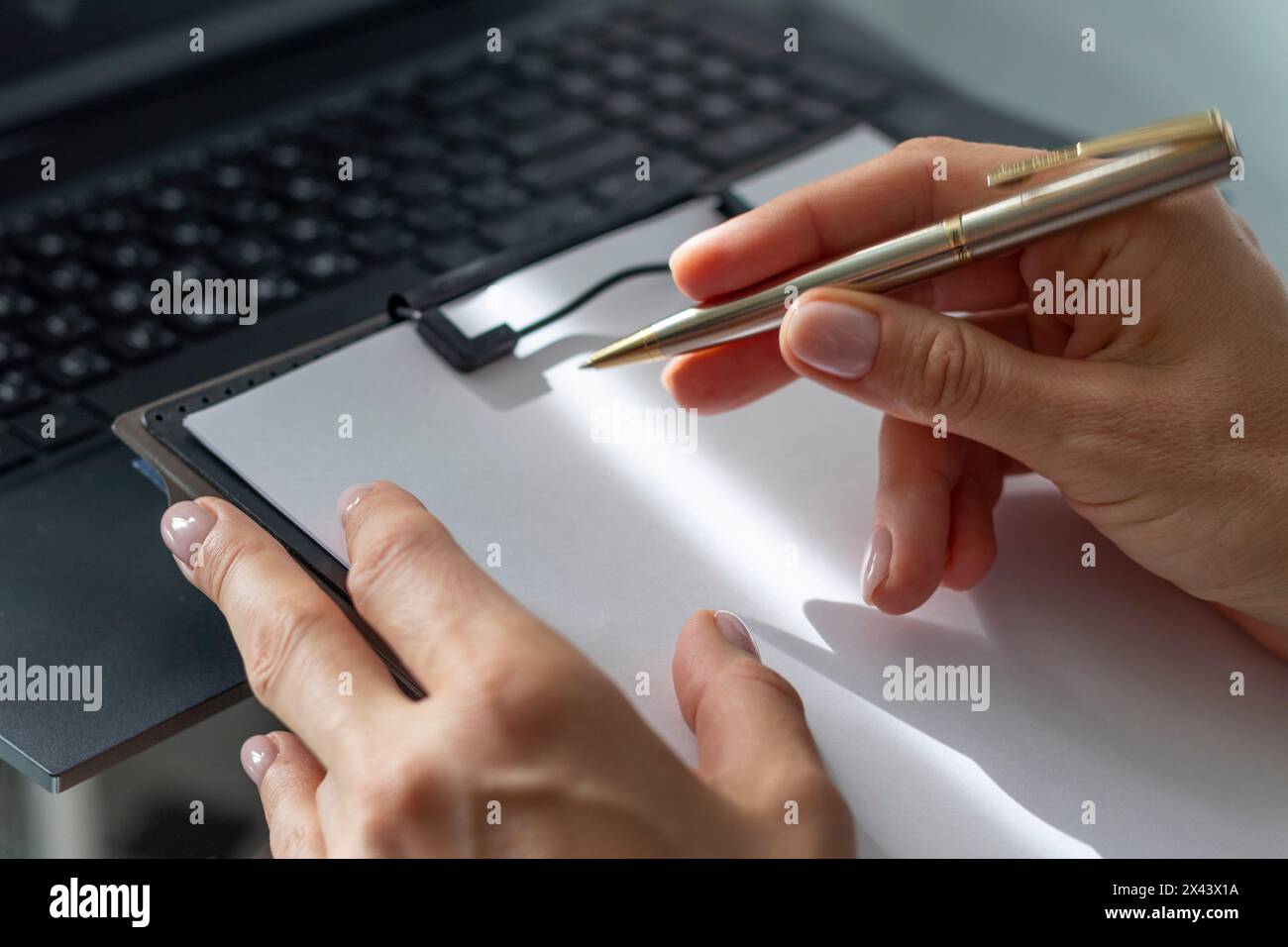 Gros plan de la femme avec de belles mains dans la tenue d'affaires, travaillant sur l'ordinateur portable dans le bureau, prenant des notes Banque D'Images