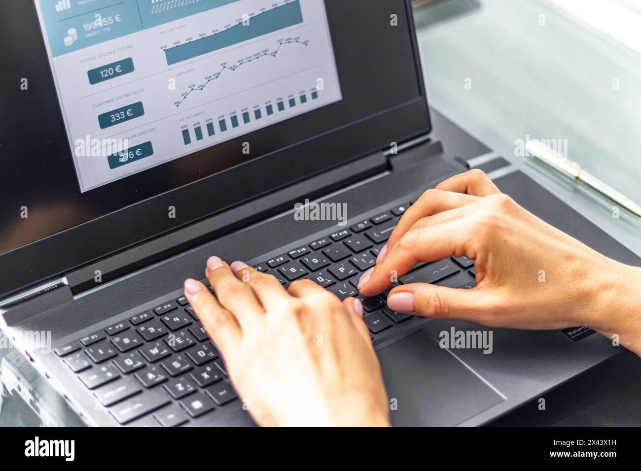 Gros plan de la femme avec de belles mains dans la tenue d'affaires, travaillant sur l'ordinateur portable dans le bureau, rapport de ventes ouvert sur l'écran Banque D'Images