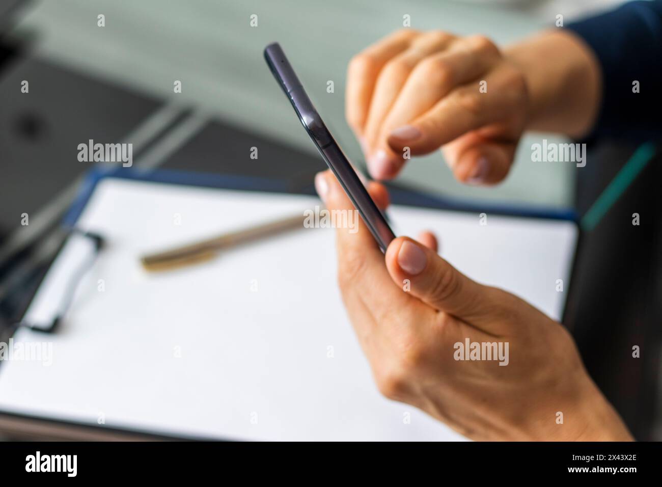 Gros plan de la femme avec de belles mains assis dans la salle de réunion pendant la réunion d'affaires, en utilisant son téléphone Banque D'Images