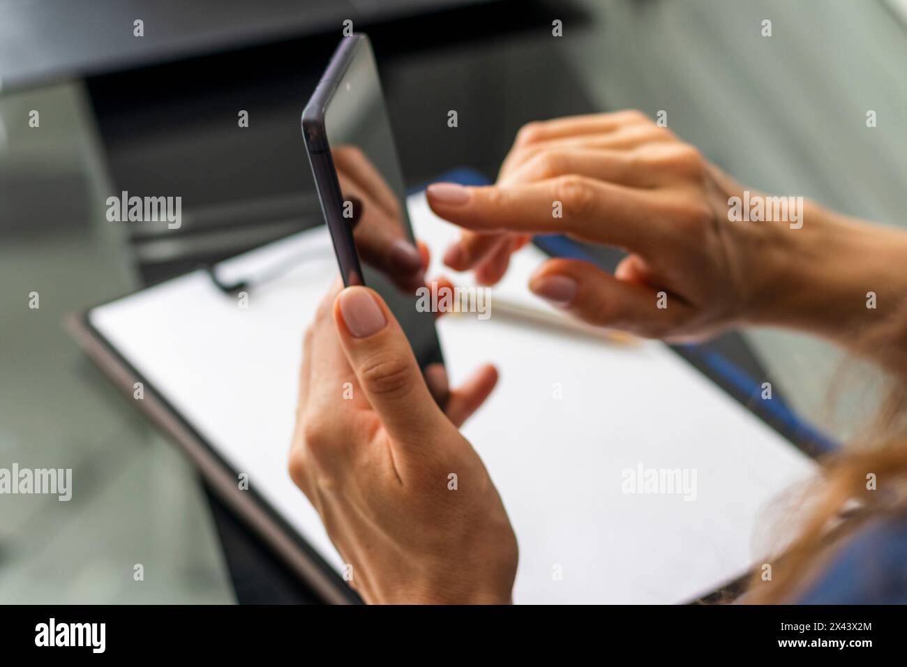 Gros plan de la femme avec de belles mains assis dans la salle de réunion pendant la réunion d'affaires, en utilisant son téléphone Banque D'Images