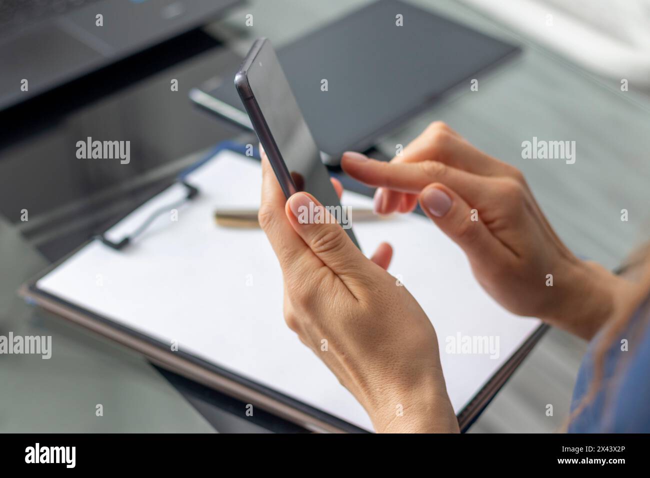 Gros plan de la femme avec de belles mains assis dans la salle de réunion pendant la réunion d'affaires, en utilisant son téléphone Banque D'Images