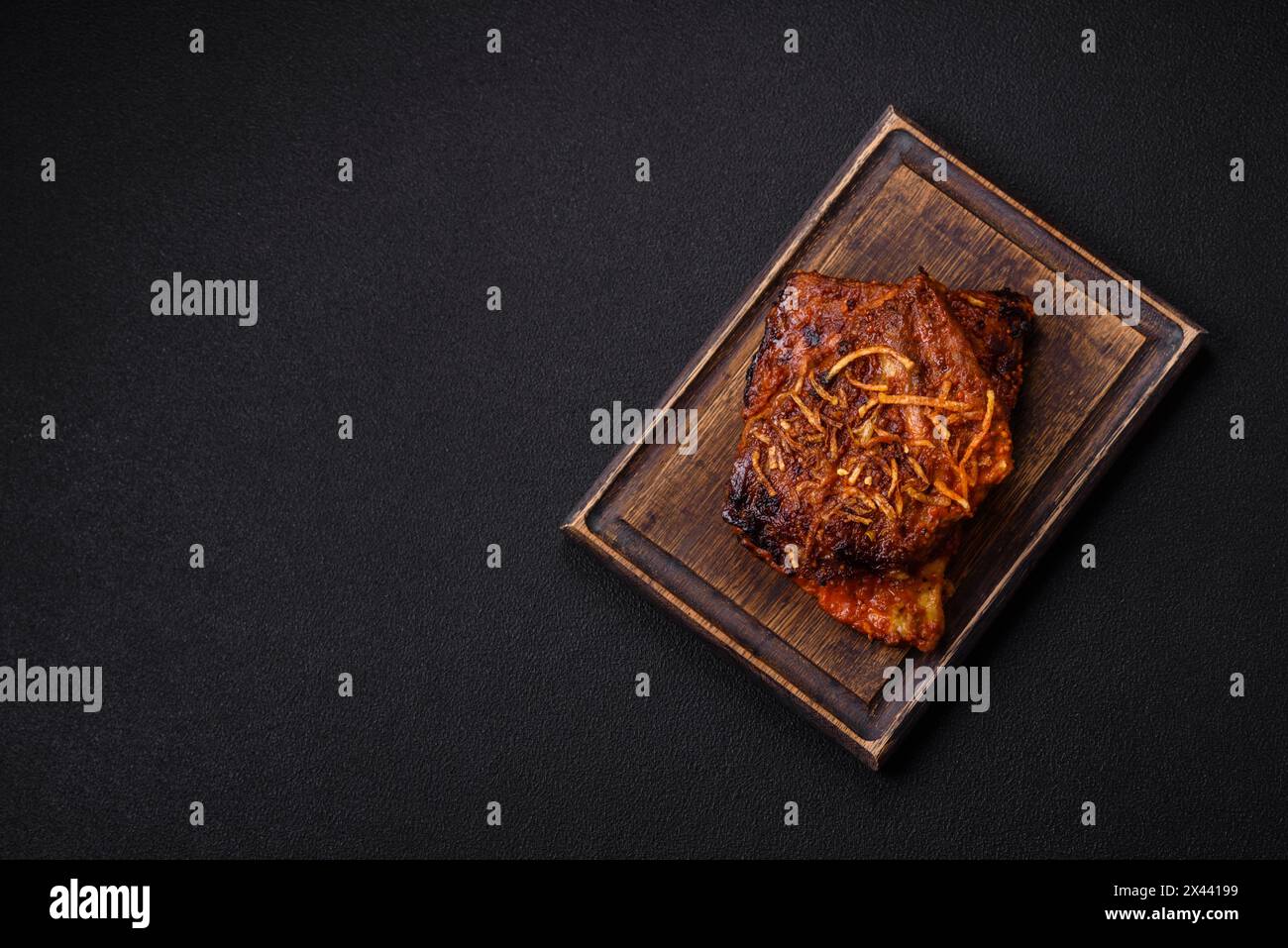 Délicieuses côtes de porc ou de bœuf cuites sur le gril avec du sel, des épices et des herbes sur un fond de béton foncé Banque D'Images