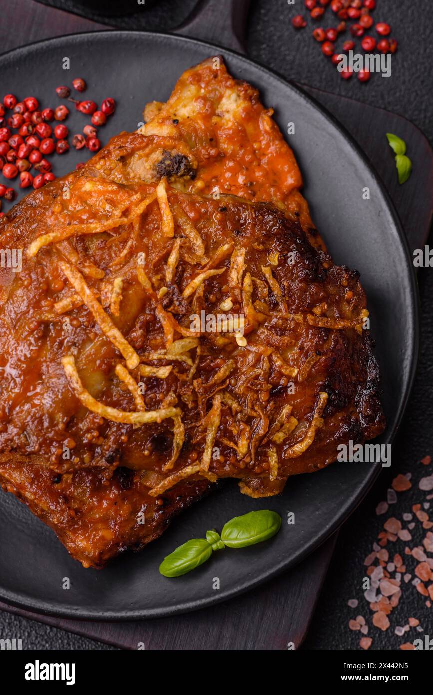 Délicieuses côtes de porc ou de bœuf cuites sur le gril avec du sel, des épices et des herbes sur un fond de béton foncé Banque D'Images