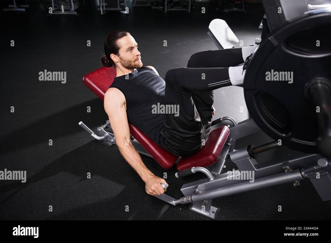 Un homme en forme dans des vêtements de sport assis contemplativement tout en haltérophilie dans un gymnase. Banque D'Images