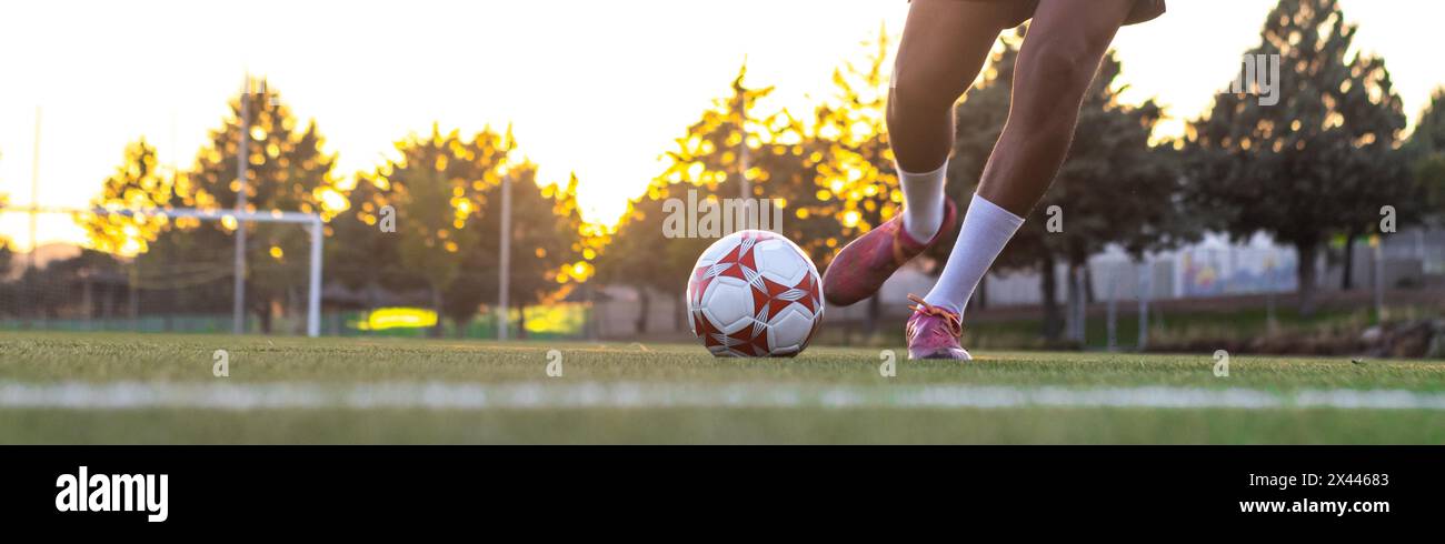 Pieds du joueur avec la balle marquant un but. Joueur de football sur le terrain en cours d'exécution avec le ballon. Pieds de joueur de football courir avec le ballon devant Banque D'Images