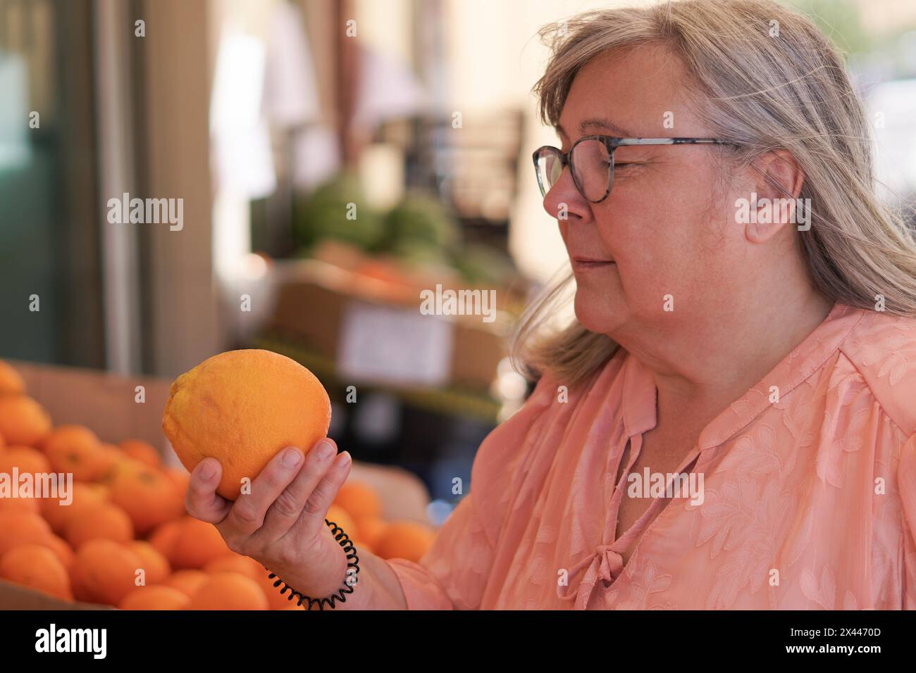 Femme âgée aux cheveux blancs achetant des oranges au marché de rue Banque D'Images